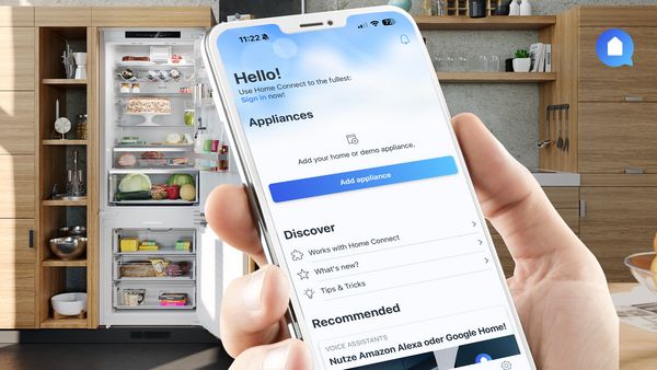 Egy kéz egy okostelefont tart, amelyen a Home Connect alkalmazás látható a beépített hűtőszekrény előtt, nyitott ajtóval, amely mögött sok étel látható