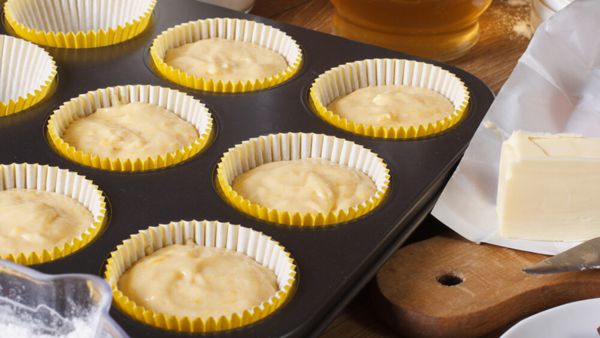 A muffin pan filled with delicious cupcakes and a pat of butter on top.