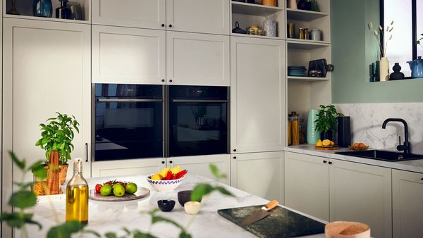 A kitchen with white cabinets and built-in ovens