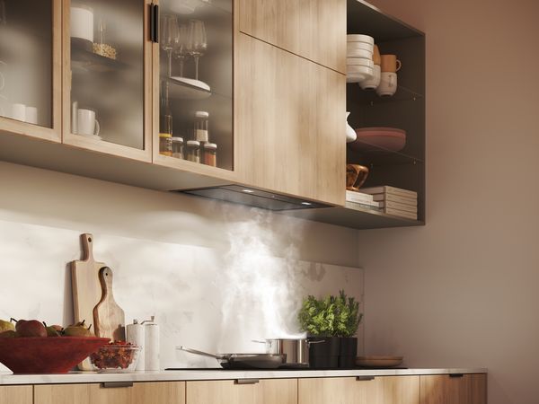 Dans une cuisine lumineuse, une hotte est parfaitement intégrée au mobilier en bois.