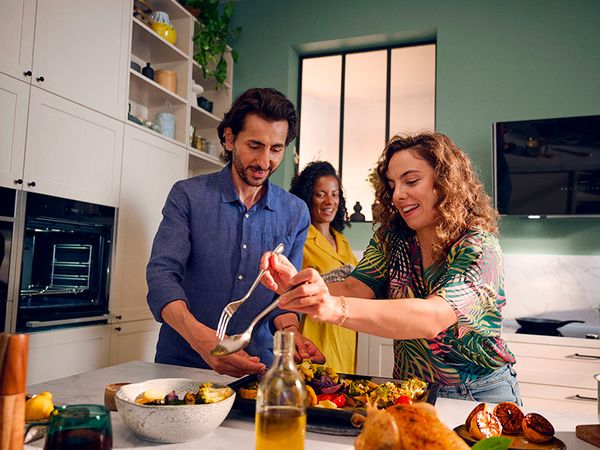 Happy family cooking together in a bright kitchen, preparing a meal with fresh ingredients.     