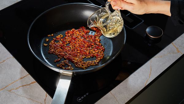 Deglazing tomato paste in a frying pan with white wine