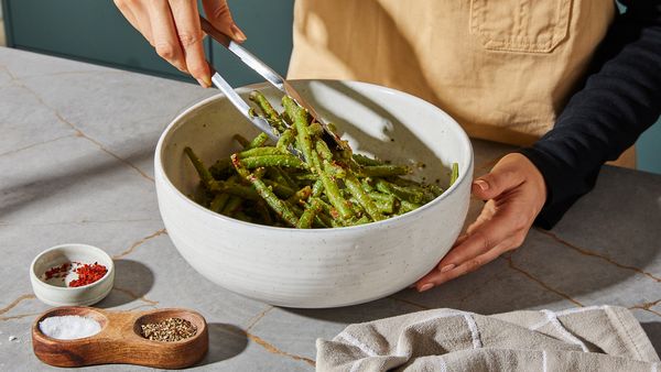 Seasoning the green beans in a bowl with a garlic-miso mixture 