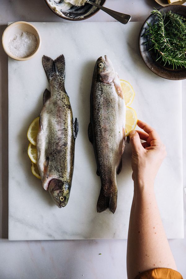 Lemons inserted into sliced trout on chopping board.