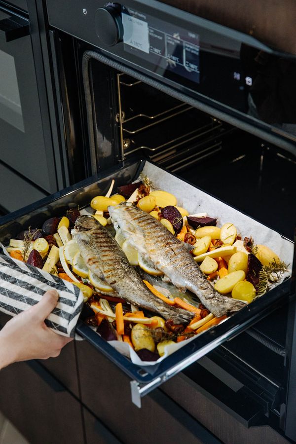 Trout removed from NEFF oven with cooked veegetables surrounding the fish on the tray.