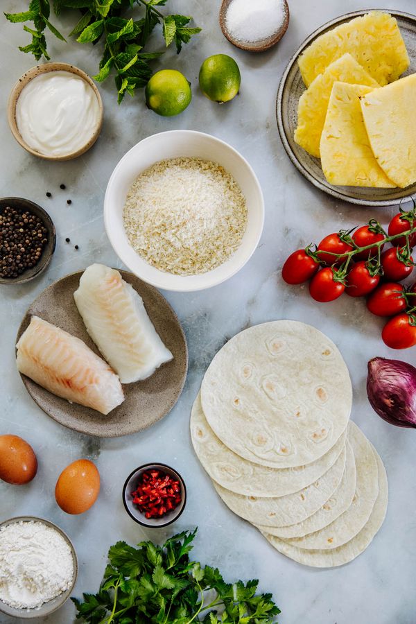 Ingredients for fish tacos recipe seperated into different plates and bowls