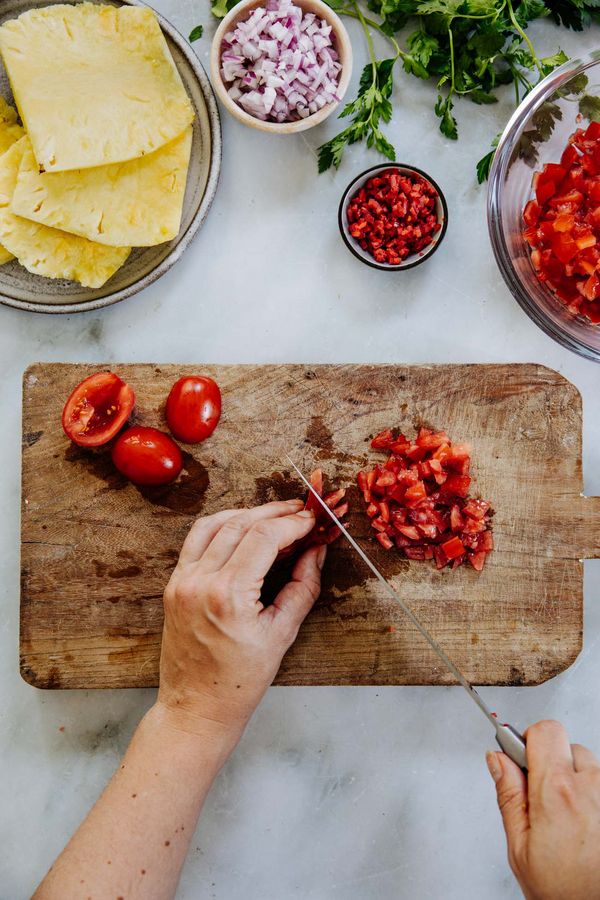 Chopping tomatoes on wooden board.