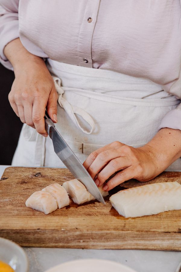 Chopping fish on wooden board to make the fillets.