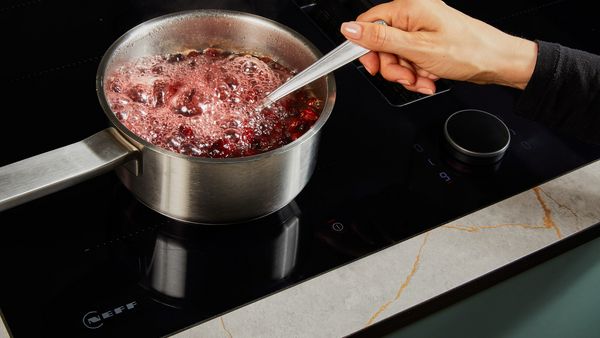 Simmering cranberry juice, dried cranberries, and sugar in a small pot