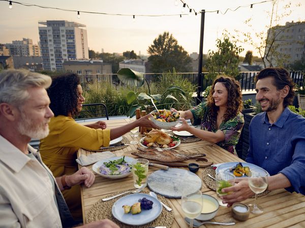 Group of friends enjoying drinks together on a rooftop at sunset.     
