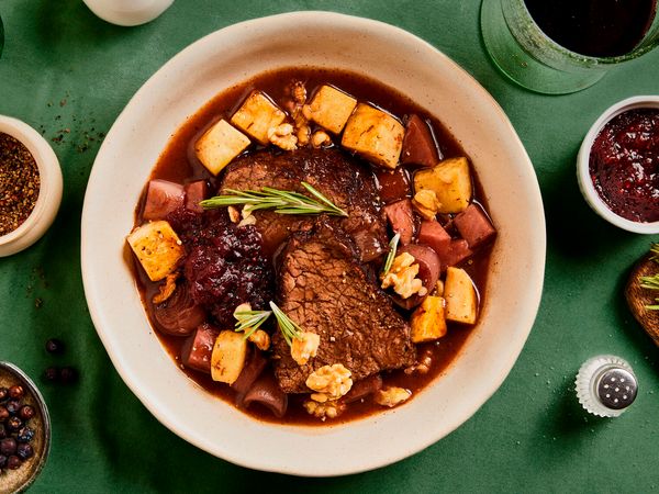 A plate with a recipe of meat in sauce on a green tablecloth