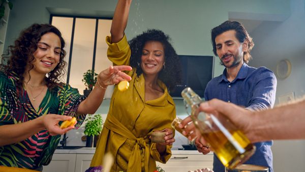 friends pouring oil from a bottle onto a tray of food