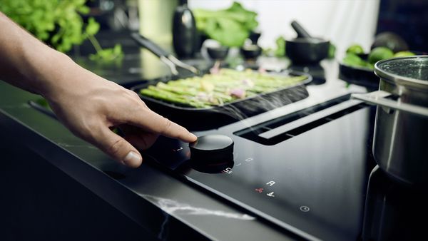 Person using black NEFF venting hob