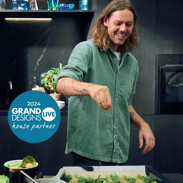 A man and woman collaborate in a kitchen, preparing a meal together with various ingredients and cooking utensils.