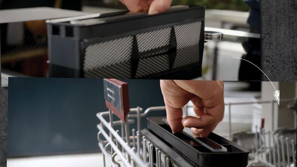 Person removing the grease filter from a vented hob and placing it into a dishwasher for cleaning