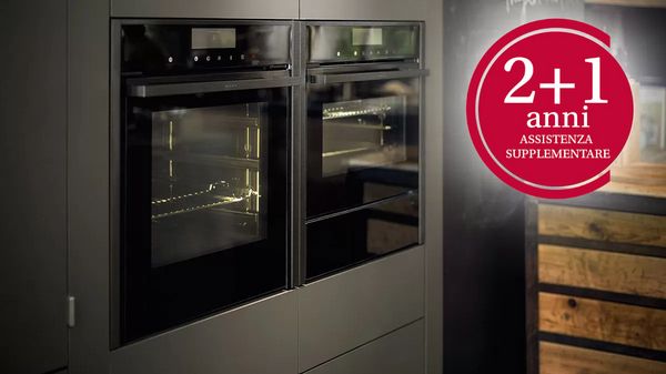 Due forni a incasso fianco a fianco in cucina moderna, con badge rosso "2+1 anni di assistenza". 