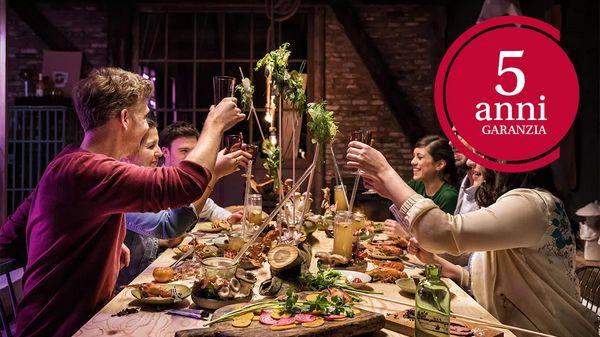 Tavola festiva con piatti colorati e brindisi alzati, celebrando insieme. 