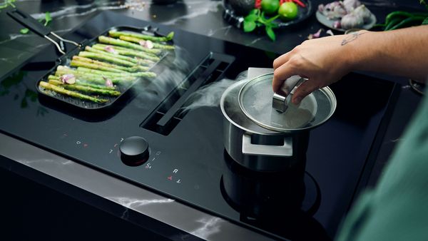 NEFF venting hob in use with pots and pans on the surface, actively venting steam