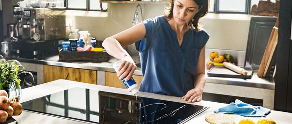 Woman cleaning an induction hob with a wet cloth