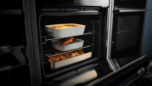 Multiple dishes of food cooking on different oven levels