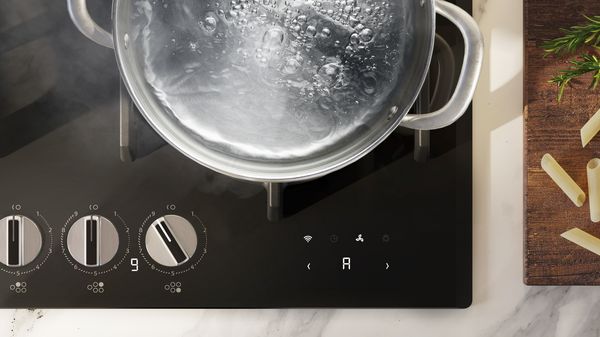 Una pentola con acqua bollente su un elegante piano cottura a gas.