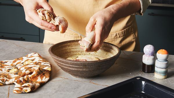 Putting marinated chicken breasts on a skewer