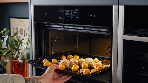 Transferring chicken breasts, potatoes and onions to an oven