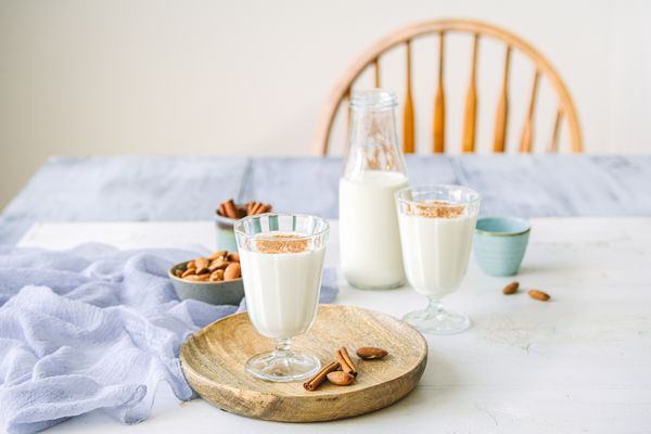 Una bottiglia aperta e due bicchieri di latte con mandorle e cannella su una tavola