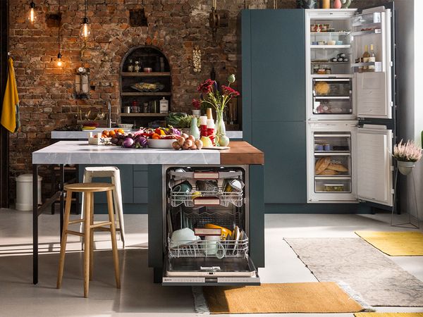 A bright kitchen scene displaying a refrigerator, sink, and table, emphasizing a practical and welcoming atmosphere.