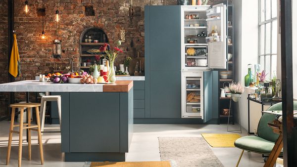 A chic kitchen that highlights a brick wall and a striking blue refrigerator, harmonizing contemporary and rustic design features.