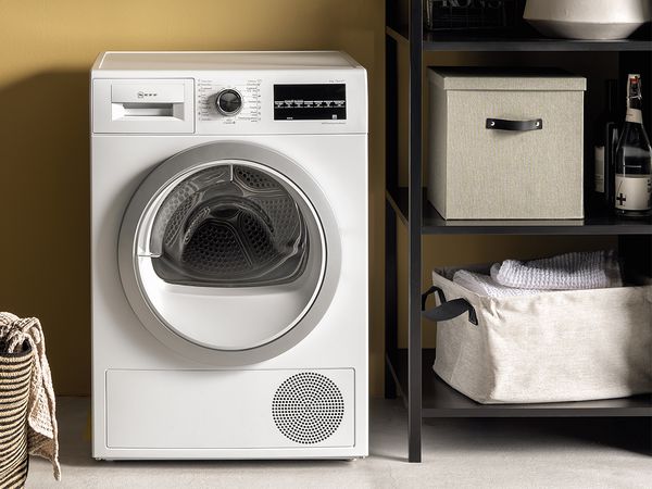 A white washing machine positioned next to two laundry baskets, one filled with clothes, in a clean and organized space.