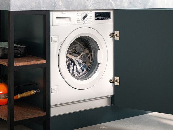 A washing machine positioned in a kitchen beside a sink, showcasing a functional and efficient laundry space. 