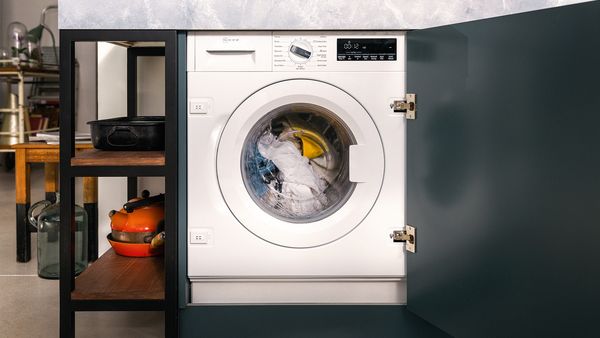 A washing machine is prominently displayed in a modern kitchen setting, showcasing its sleek design and functionality.  