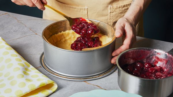 Die Sauerkirschfüllung aus dem Edelstahlkochtopf auf den Teig in der Backform gießen.