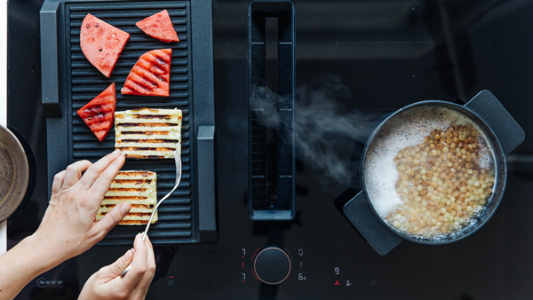 A person skillfully cooks food on a grill, utilizing a frying sensor for optimal temperature control.