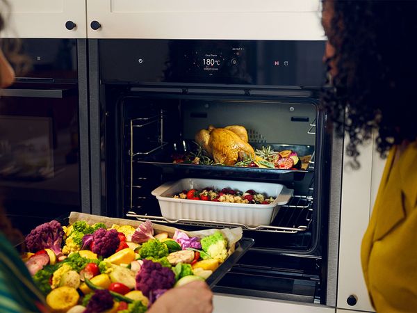 A woman carefully removes a tray of delicious desserts from the oven, showcasing her culinary skills and creativity.