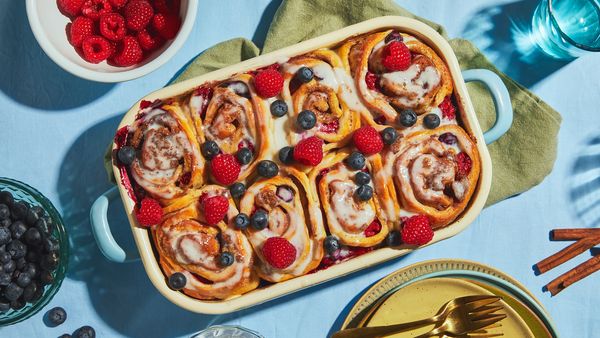 Cinnamon rolls with berries in baking tray on a table