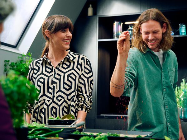 Coppia di ragazzi sorridenti che cucina insieme in una cucina luminosa