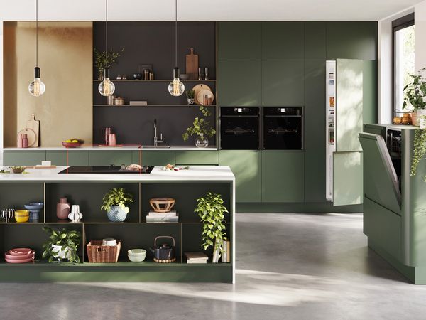  A modern kitchen featuring green cabinets and matching green appliances, creating a cohesive and vibrant design.  