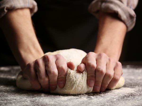 Mani che lavorano l’impasto della pizza