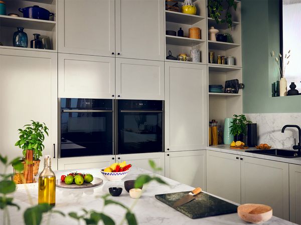 A modern kitchen featuring white cabinets and a stainless steel sink, creating a bright and clean cooking space.