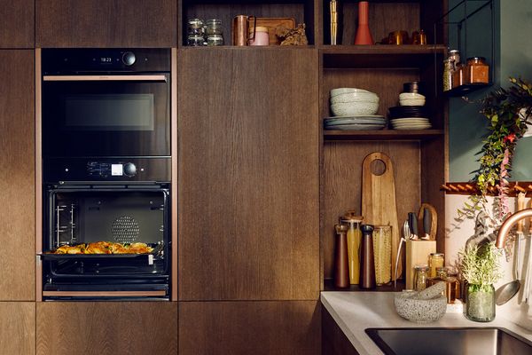 Una cucina moderna con forno integrato e cibo arrosto, armadietti in legno e utensili e decorazioni ordinati