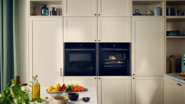 A modern kitchen featuring white cabinets, a built-in oven, and a stove for cooking. 