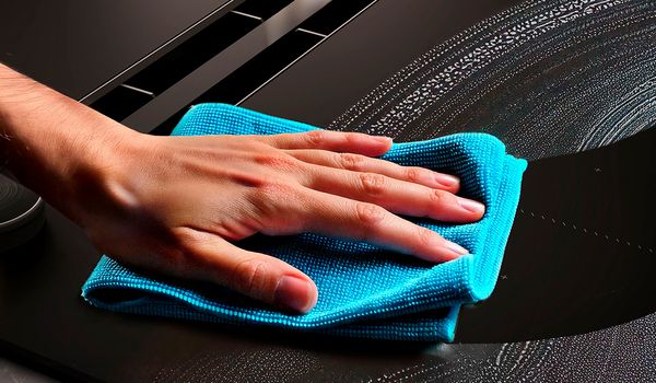 Έναχέρι με μπλέ πανί που καθαρίζει την εστία.