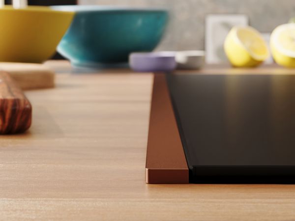 Matzwarte kookplaat met Brushed Bronze Flex Design-zijlijst en houten werkblad