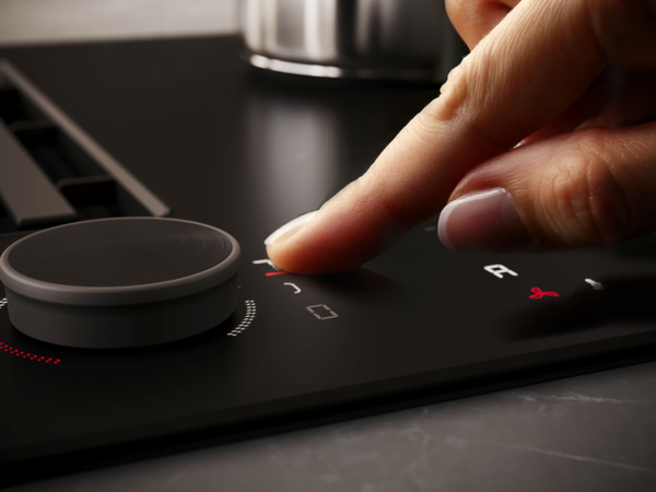 Finger bedient die Touchfläche eines NEFF Matt Black Induktionskochfelds direkt neben dem Twist Pad Flex® Drehregler.