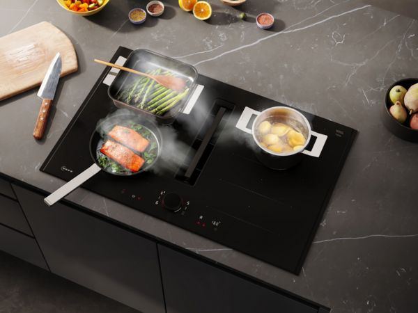 Drie pannen op de matzwarte kookplaat met afzuiging, de stoom verdwijnt effectief in de afzuiging