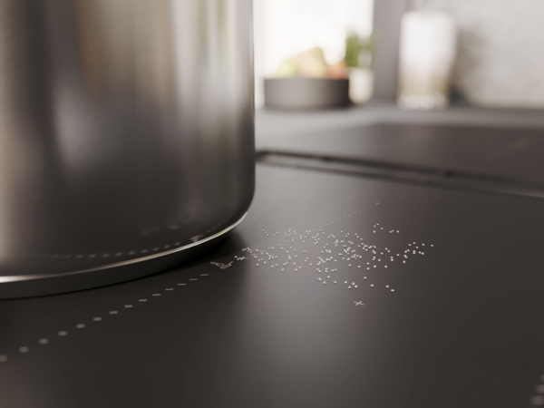 Nahaufnahme eines Kochtopfs auf einem NEFF Induktionskochfeld mit Matt Black Oberfläche, sichtbar sind feine Salzpartikel auf der Glaskeramik.