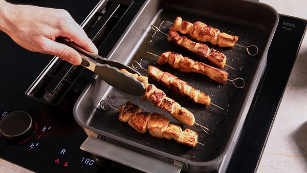 Hähnchenstücke werden auf Grillspießen gebraten.