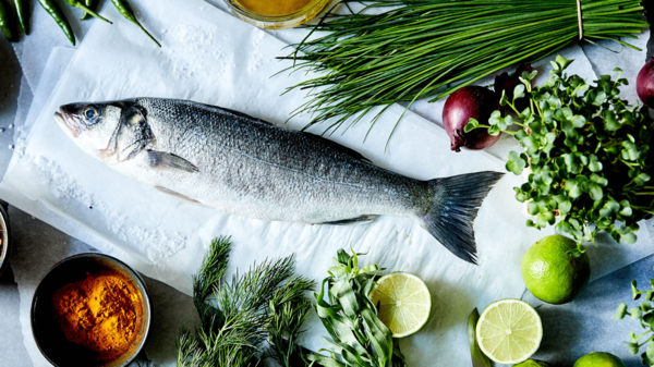 Ganzer Seebarsch mit verschiedenen Lebensmitteln